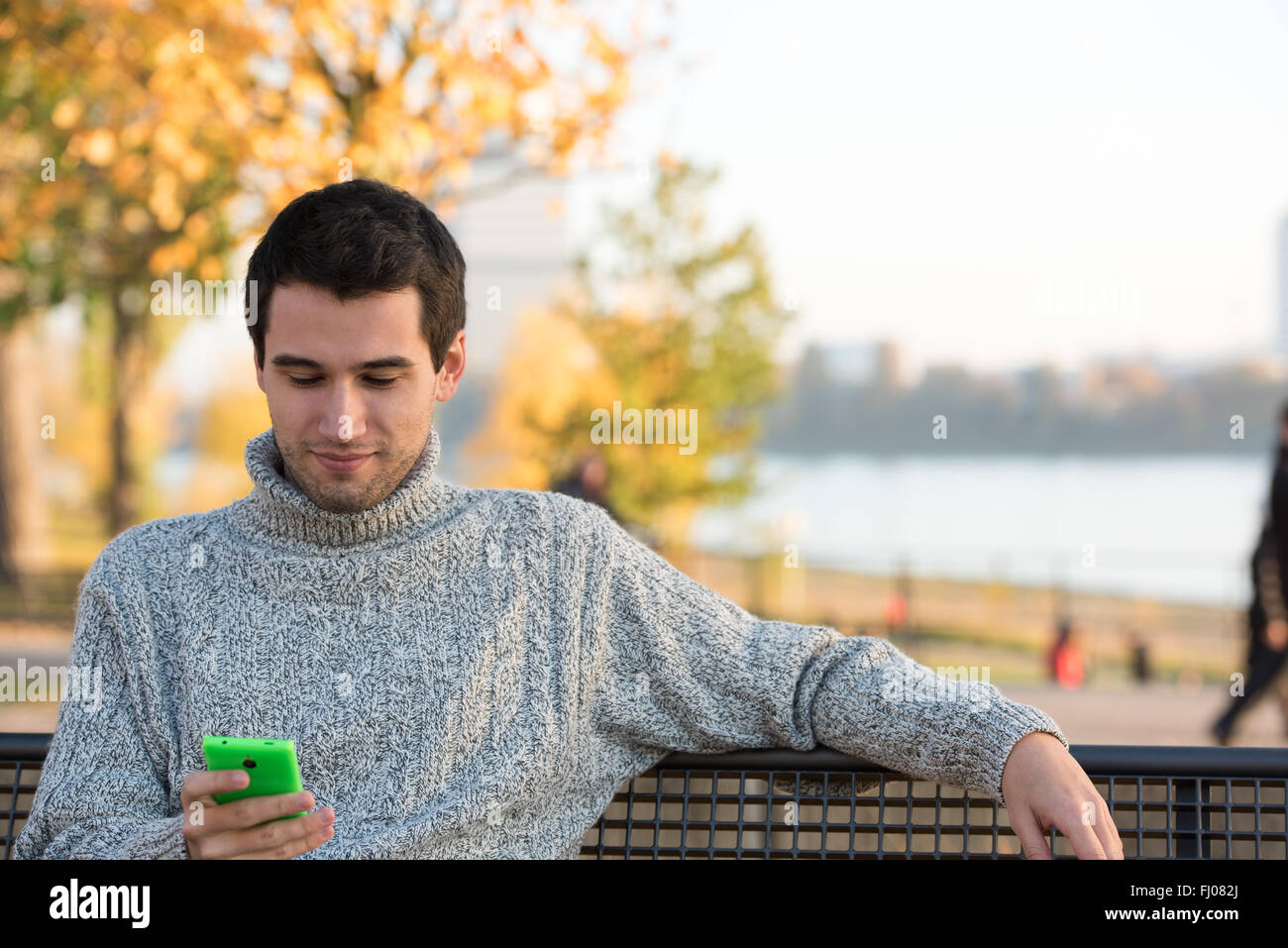 young man in park sitting on bench, speaking on the smart phone Stock Photo