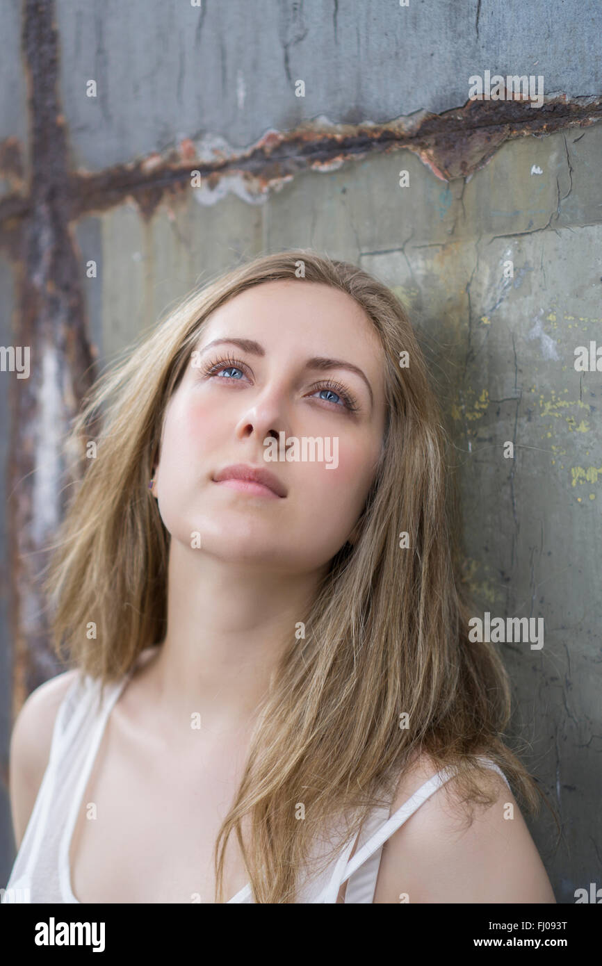 Young woman leaning against a rusty wall Stock Photo