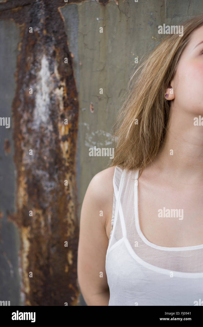 Young woman leaning against a rusty wall Stock Photo