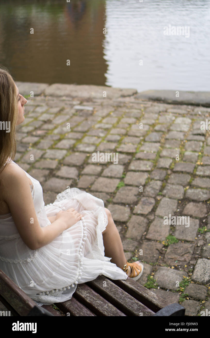 Woman sat on the bench by the canal Stock Photo