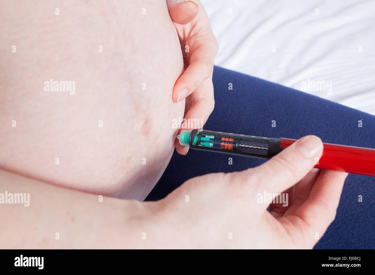 A nine month pregnant woman injects her stomach with slow acting insulin (Levemir) to control her Type 1 diabetes. Stock Photo