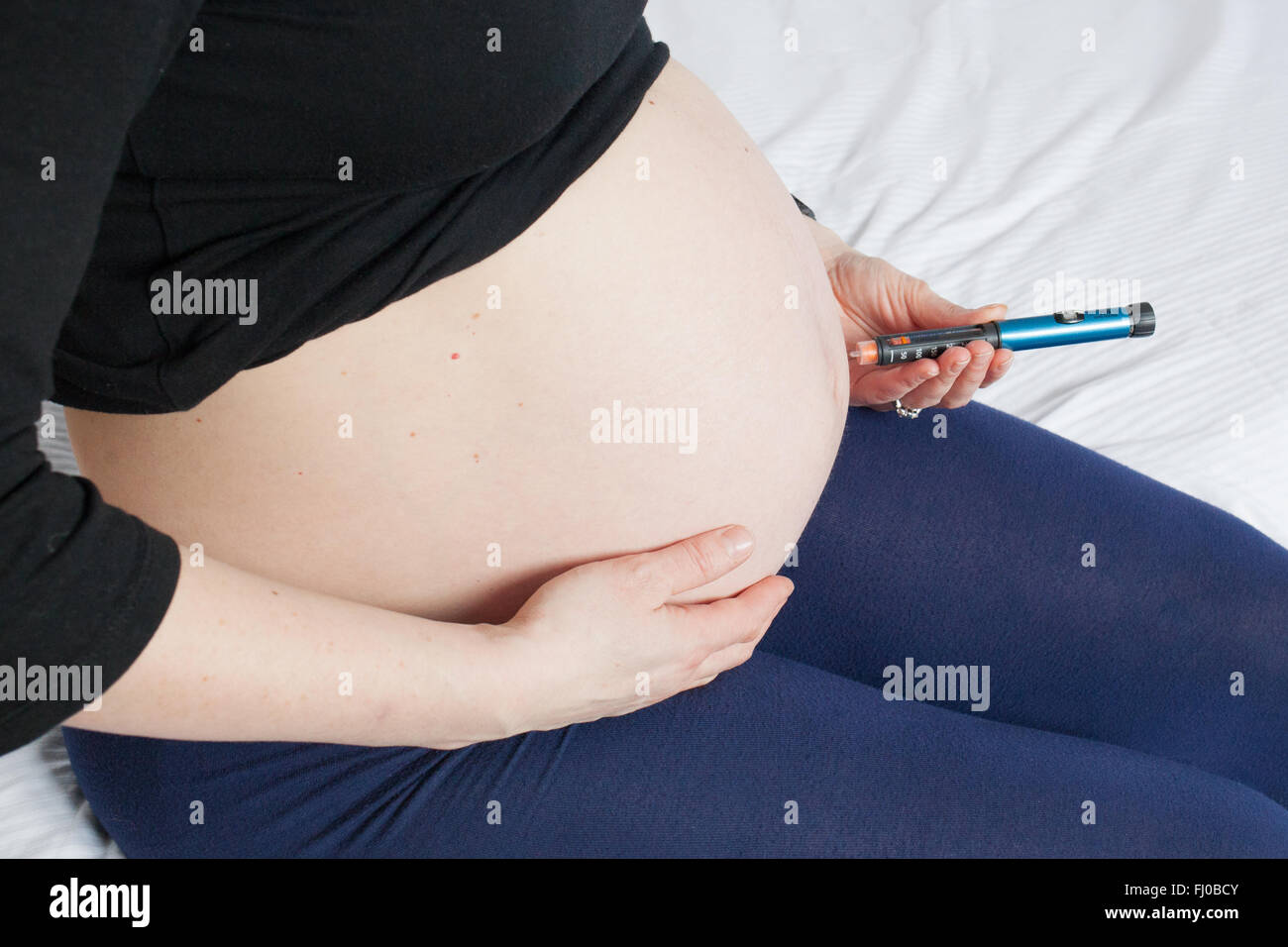 A nine month pregnant woman injects short acting insulin (Novorapid)  into her stomach to control her Type 1 diabetes. Stock Photo