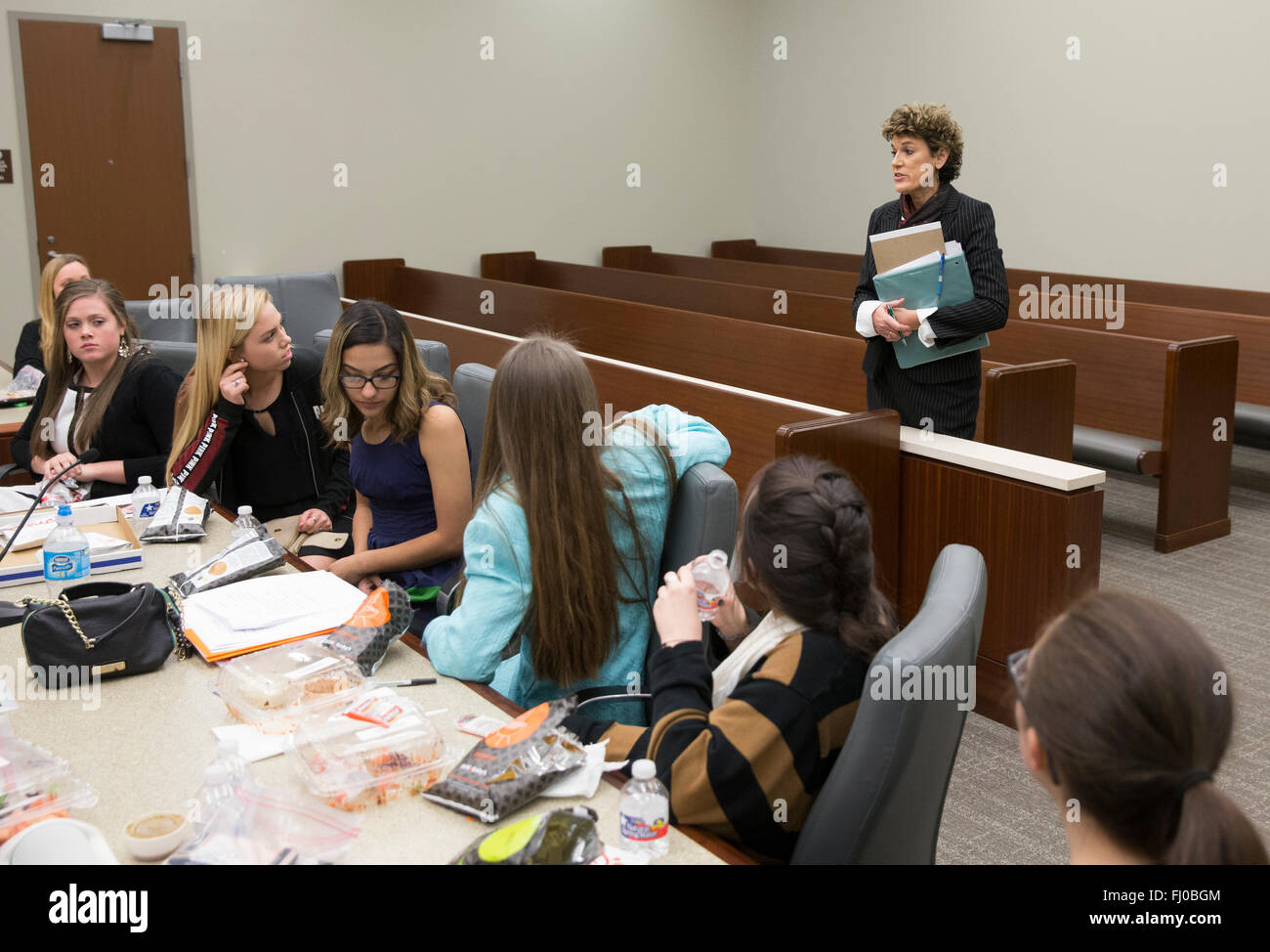 High school students serving as defense team in mock trial listen to event organizer during deliberations Stock Photo