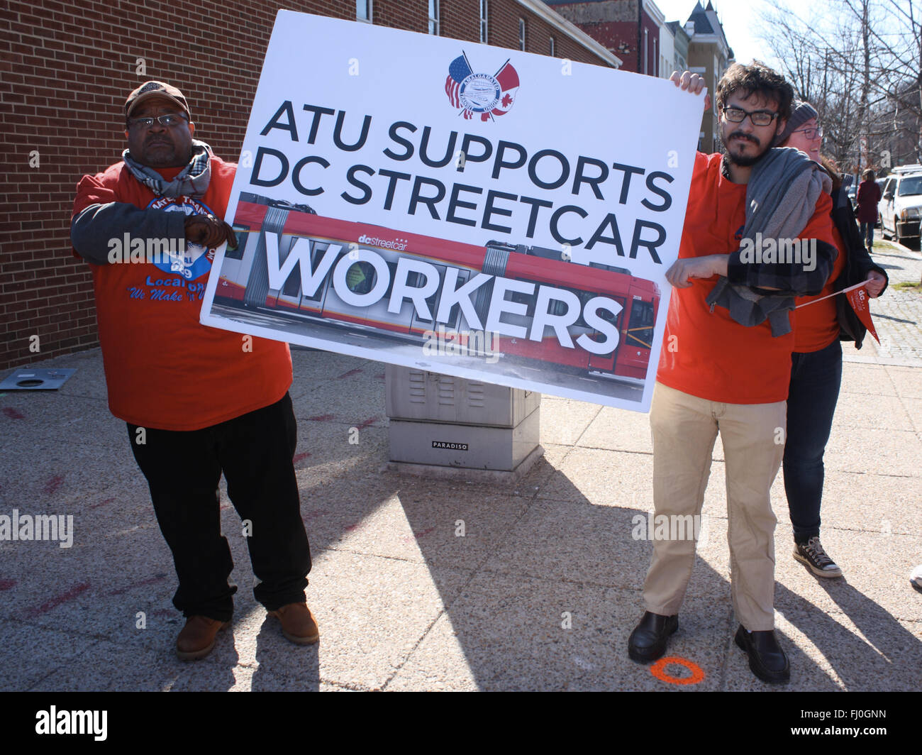 Washington, District of Columbia, USA. 27th Feb, 2016. Two people holding a sign that reads, ''ATU Supports DC Streetcar Workers'' (part of a larger group standing across H Street from the ceremony celebrating the launch of the DC Streetcar). Based on the logo on the shirts being worn, ATU appears to stand for ''Amalgamated Transit Union'' on this sign. Credit:  Evan Golub/ZUMA Wire/Alamy Live News Stock Photo