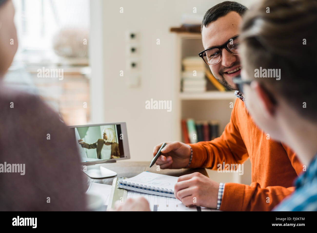 Colleagues discussing in office with video film on digital tablet in background Stock Photo