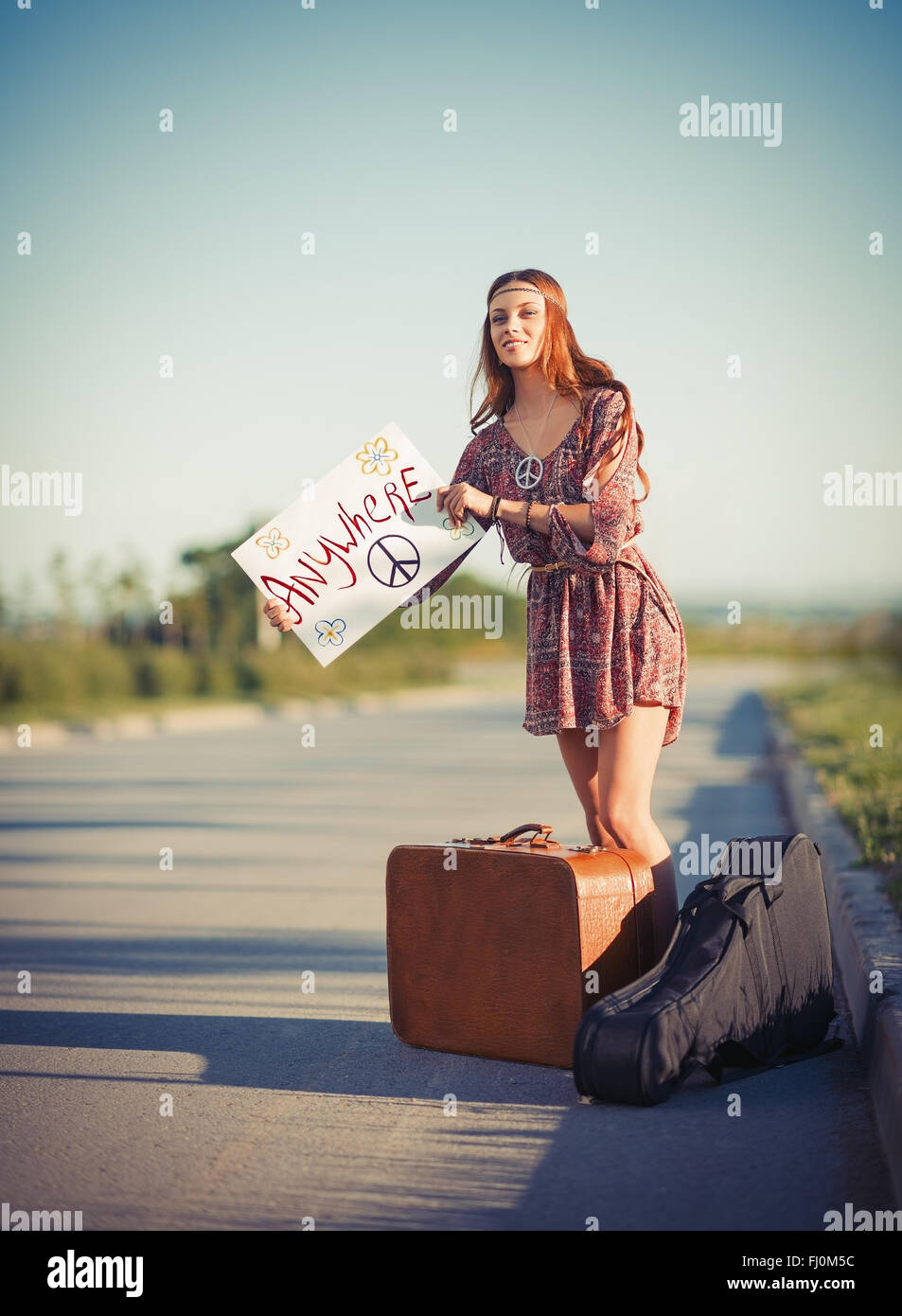 Portrait of a beautiful young hippie woman hitchhiking on the road Stock Photo