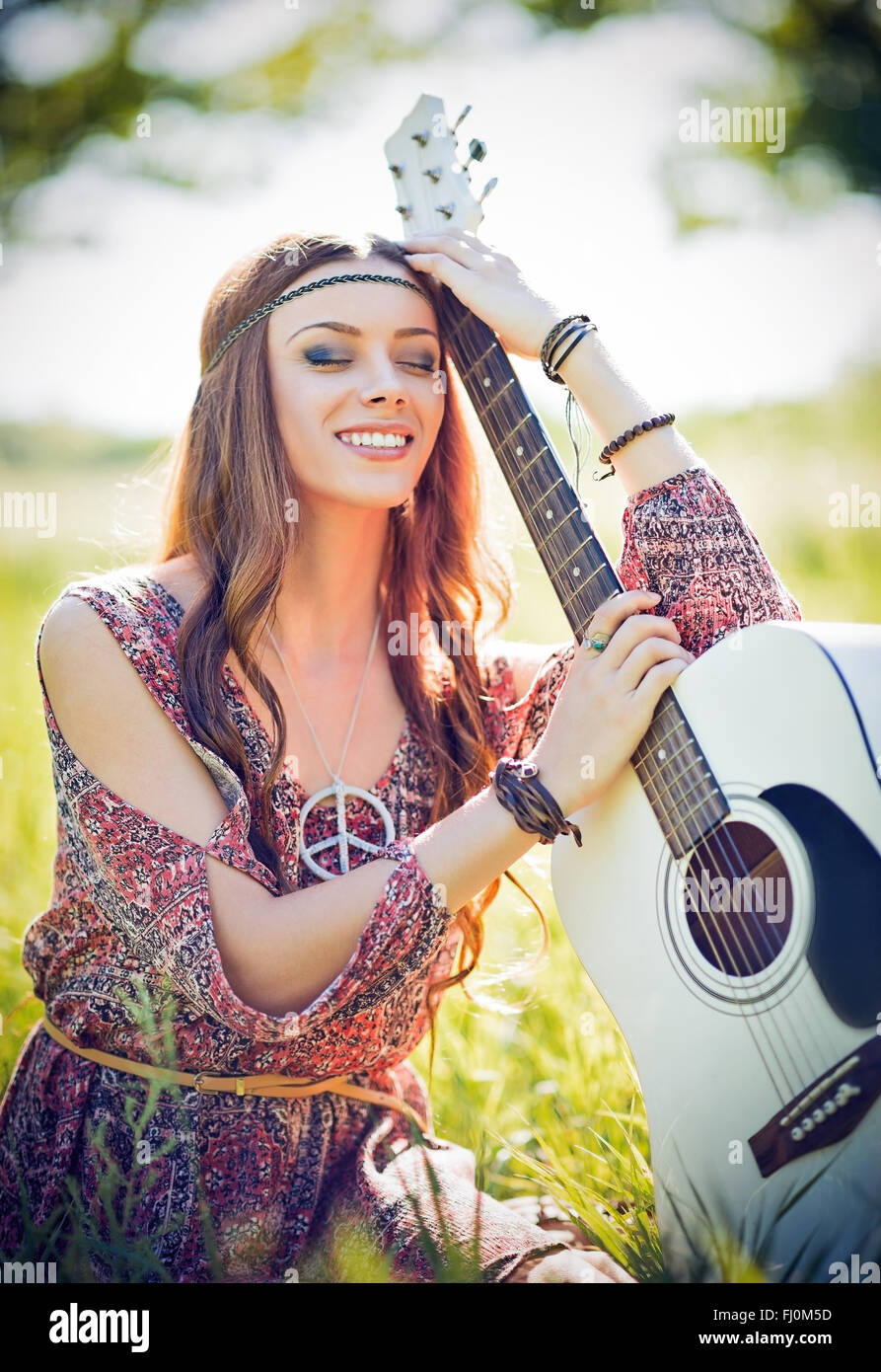 Portrait of a beautiful smiling hippie woman with guitar. Outdoor shot Stock Photo