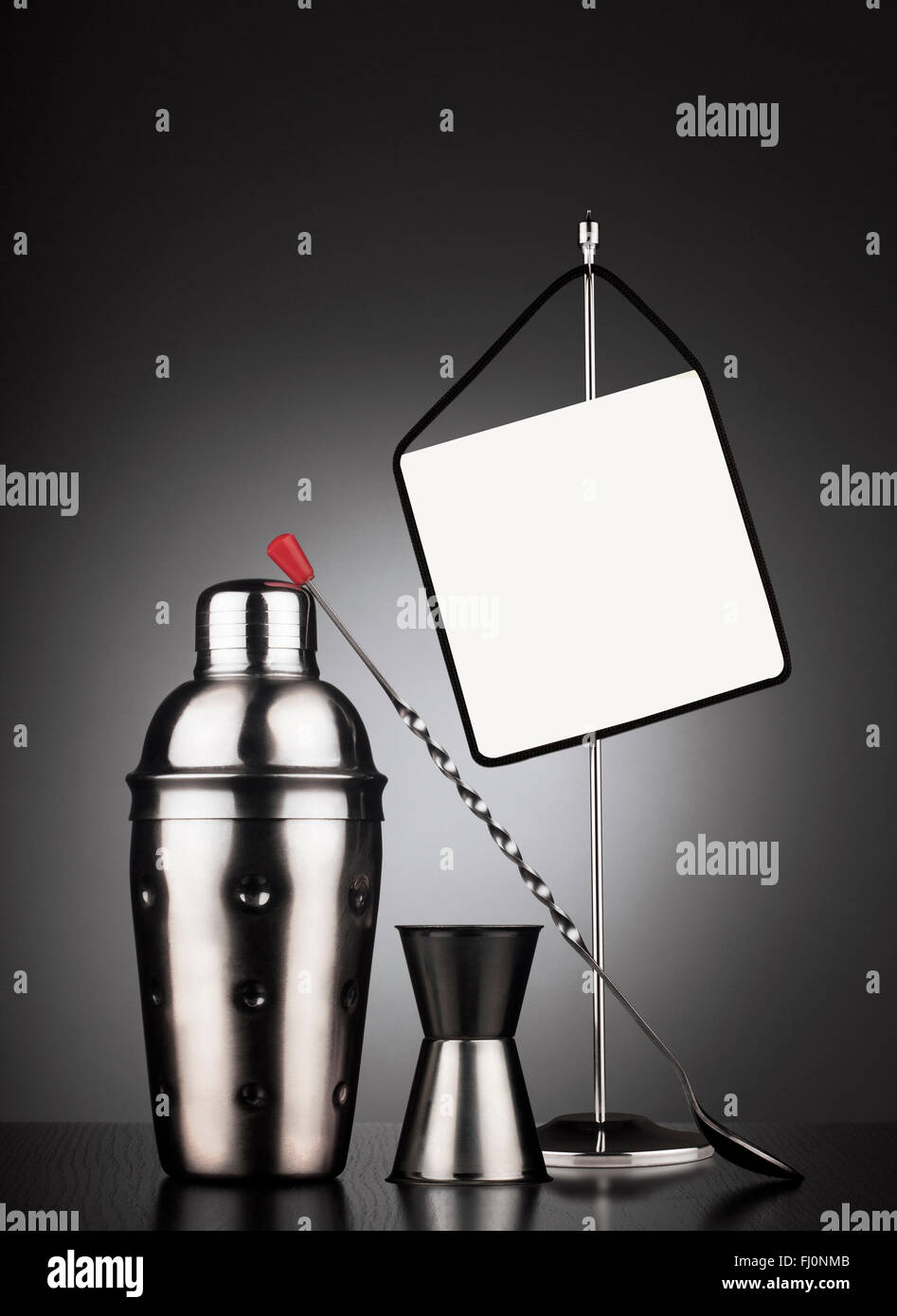 Cocktail set of tools including shaker and spoon next to a table stander with display area for