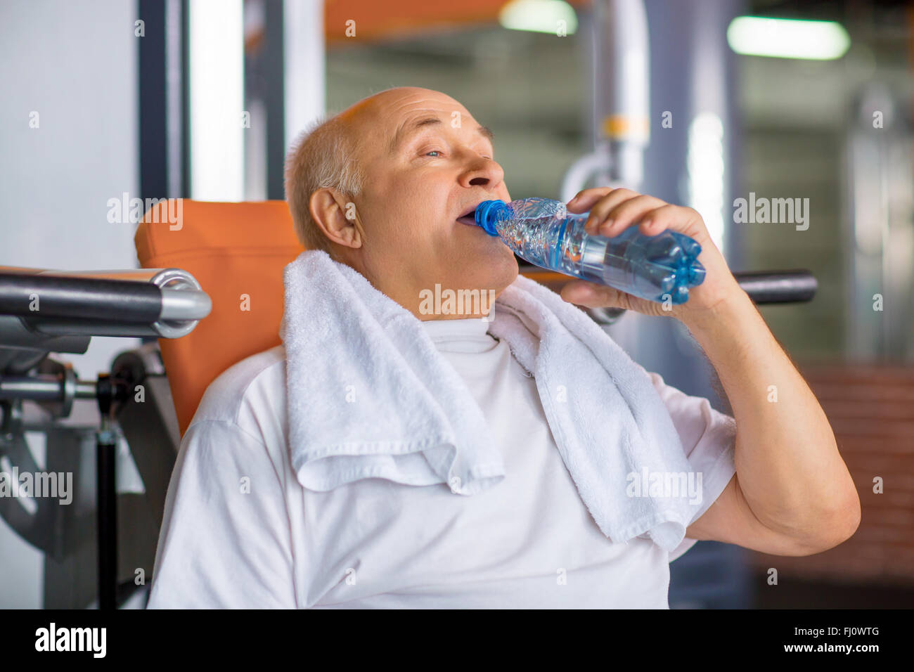 Pleasant senior man drinking water in gym Stock Photo - Alamy