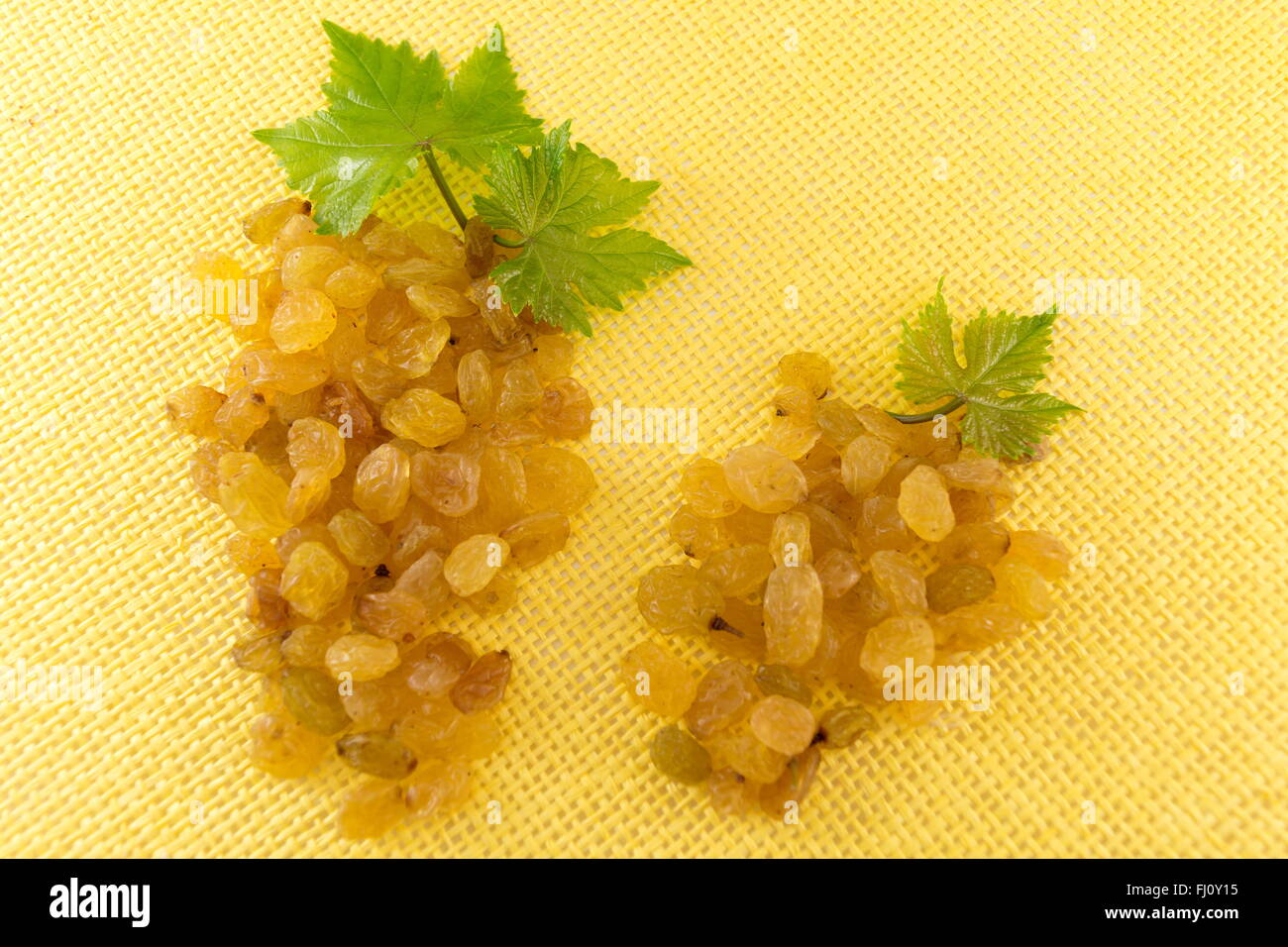 Raisins forming a grape clusters on yellow background Stock Photo
