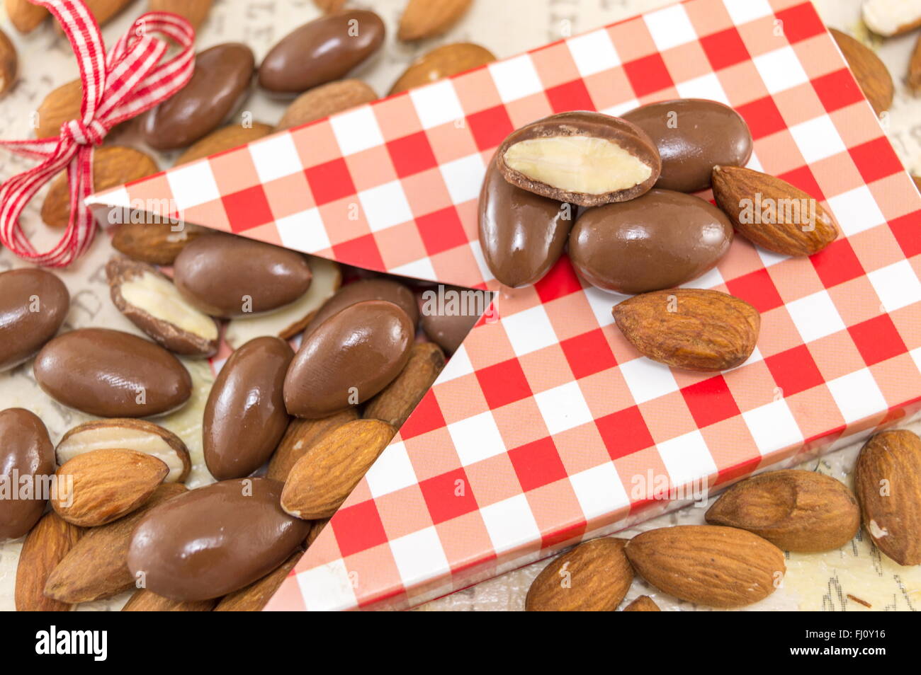 Fresh and chocolate covered almonds falling out of decorated box Stock