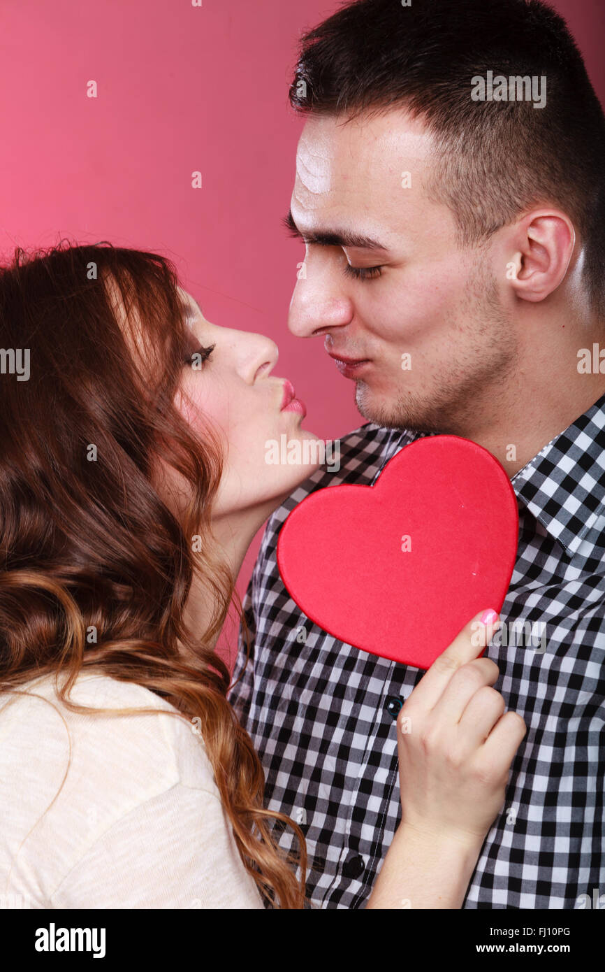Young happy loving couple kissing behind red heart - sign symbol of ...