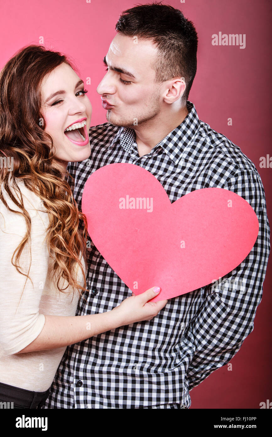 Romantic couple on valentines day. Happy joyful man and blinking woman holding heart symbol. Love concept. Stock Photo