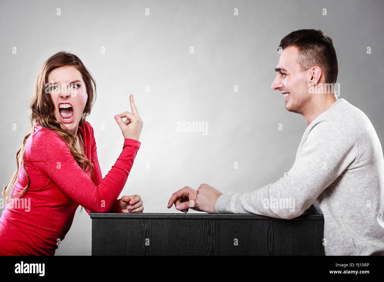 Crazy woman showing middle finger gesture to man. Insane girl gesturing