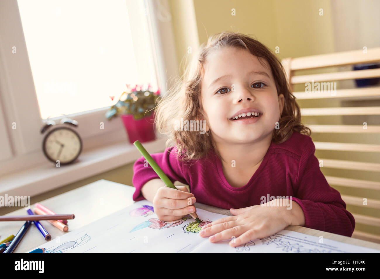 Portrait of smiling little girl painting with coloured pencils Stock ...