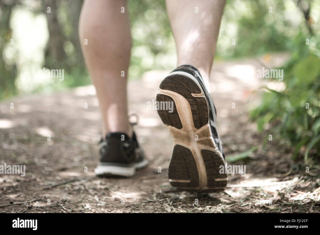 Close-up of feet of man running in forest Stock Photo
