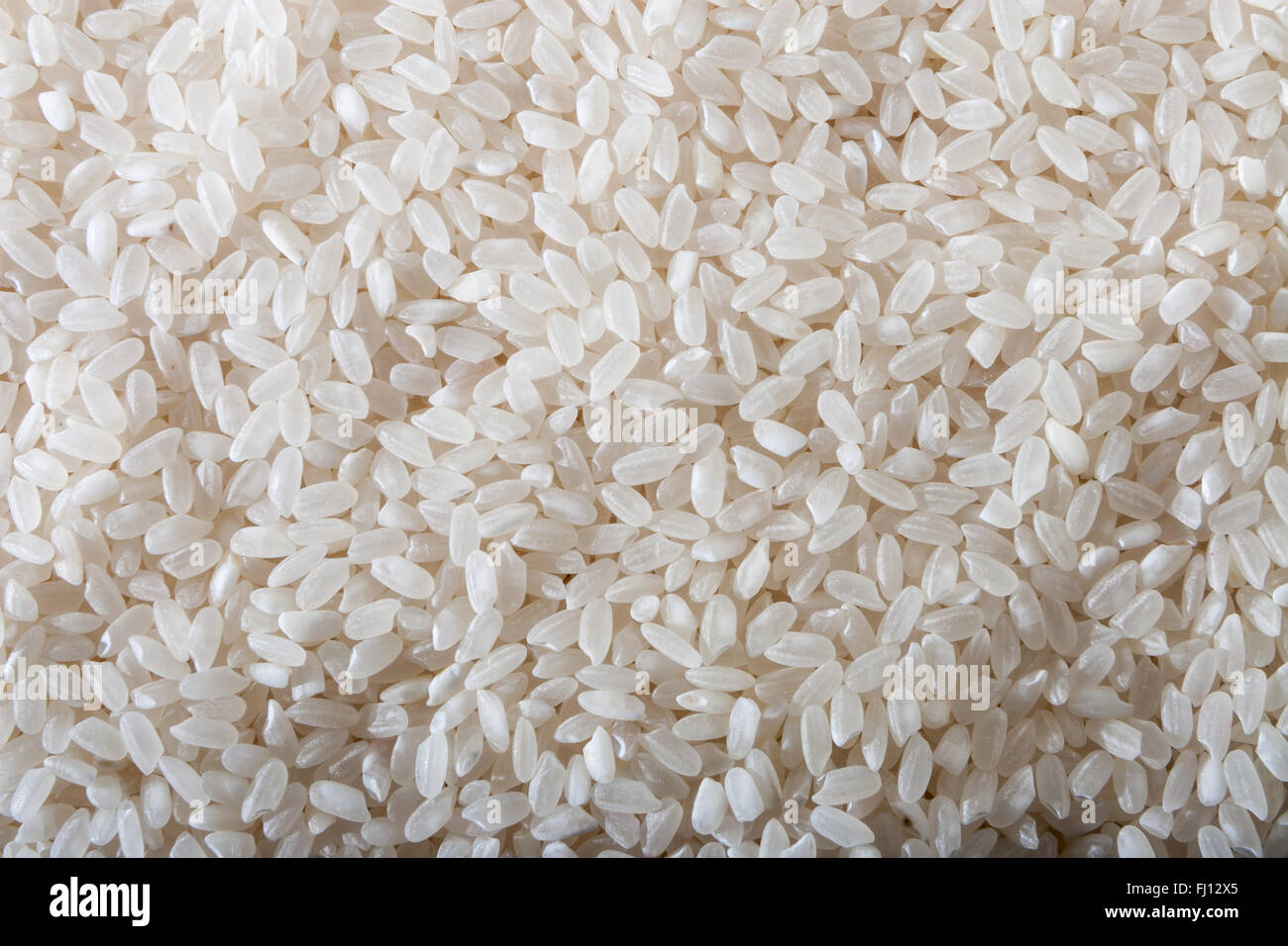 Uncooked raw white rice background Stock Photo - Alamy