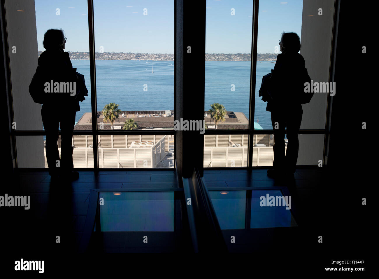 Woman reflected in mirror looking out window of Windham Hotel on San Diego Bay Stock Photo