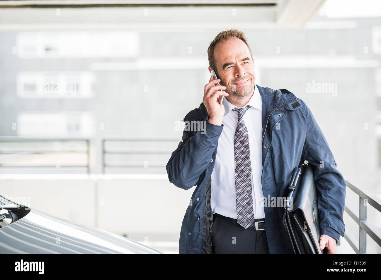 Businessman on cell phone in car park Stock Photo