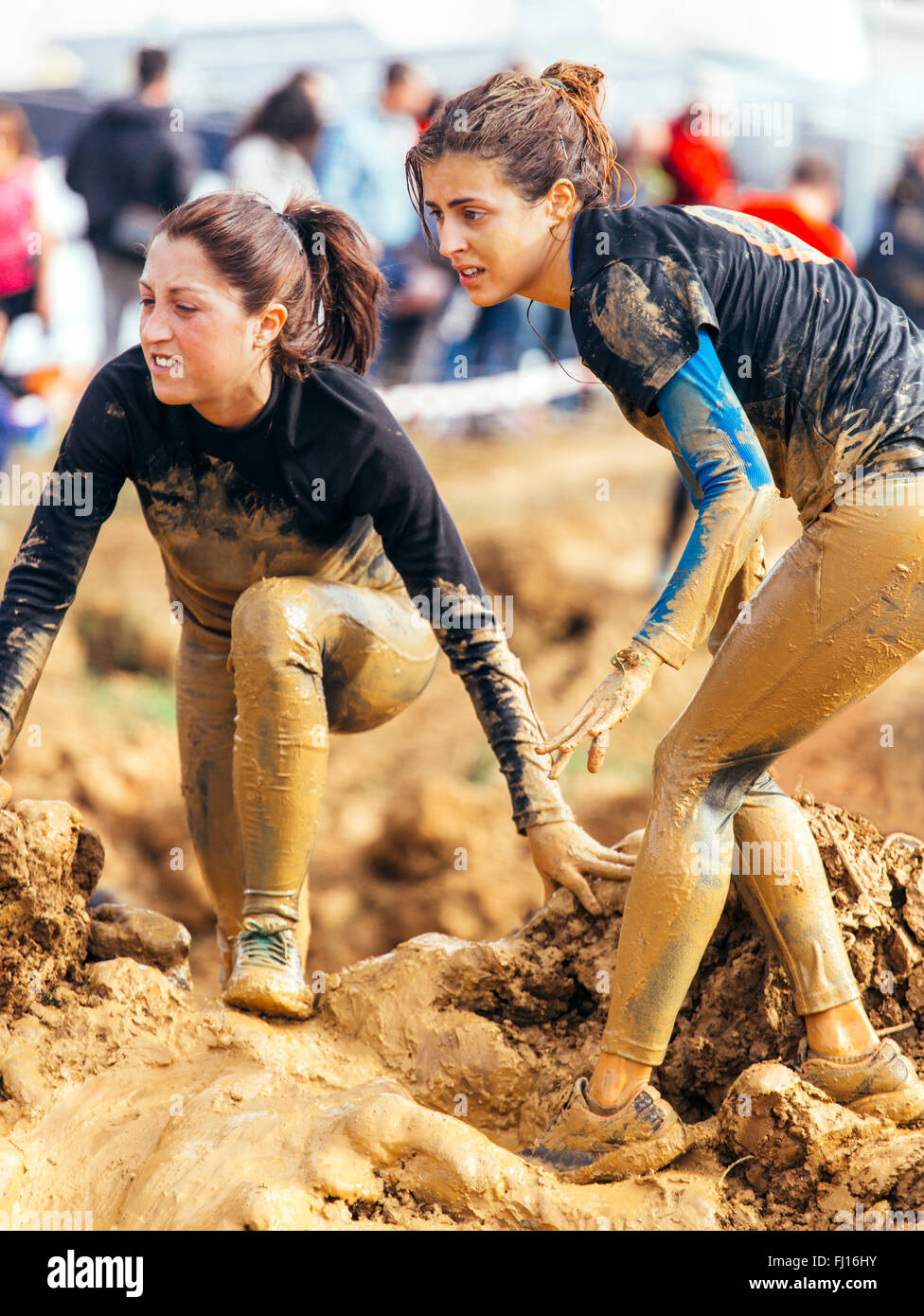 Participants in extreme obstacle race, running through mud Stock Photo