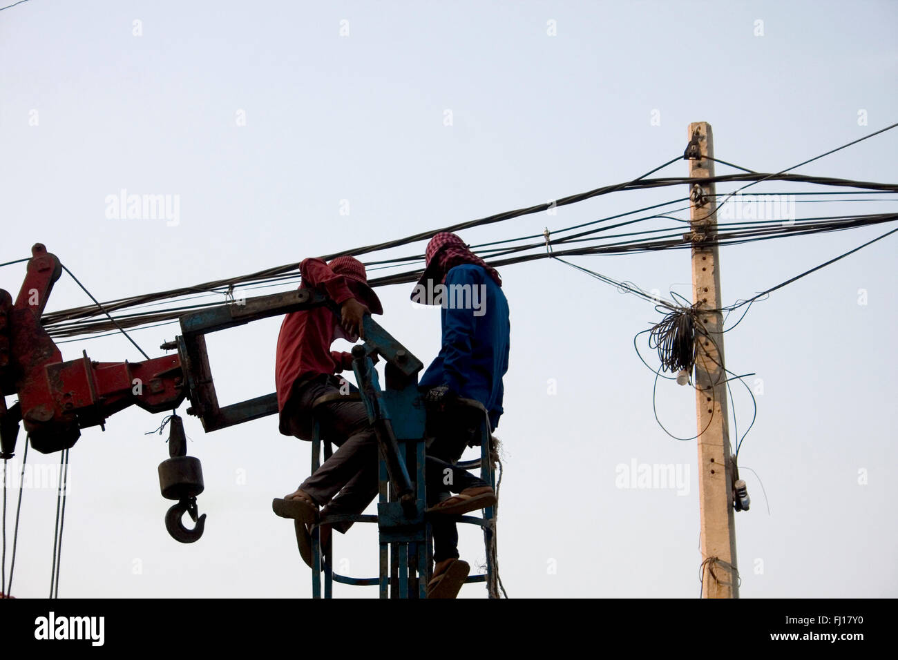 Two men are working on power and telephone lines above a new market in