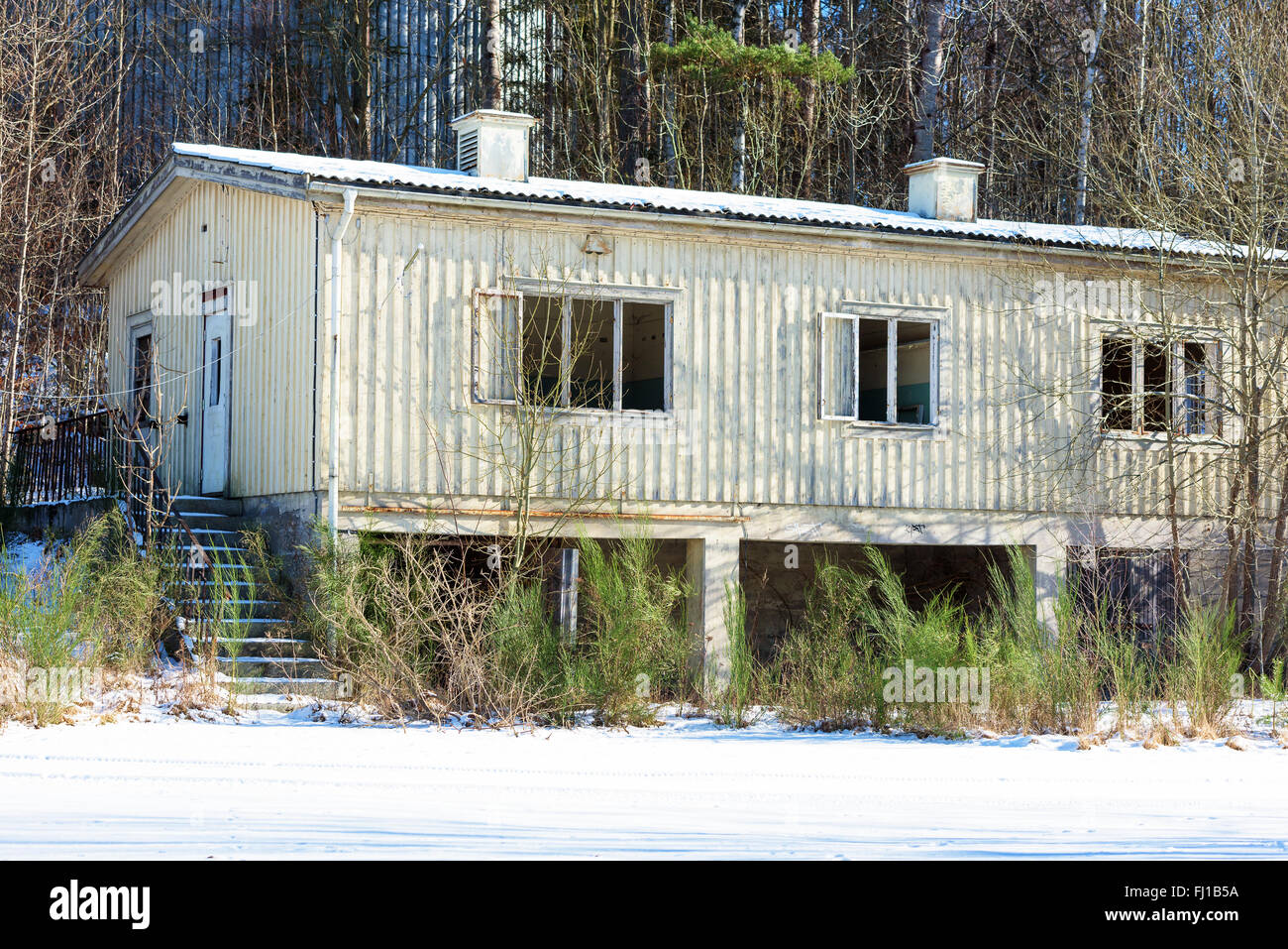 An old wooden office building on an industrial area that has been abandoned. The house is weathered and broken. All the windows Stock Photo