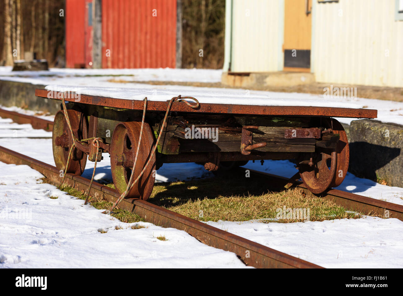 A very small railway cart or wagon standing outside ab old station building with a thin layer of snow on it. The wagon is very r Stock Photo