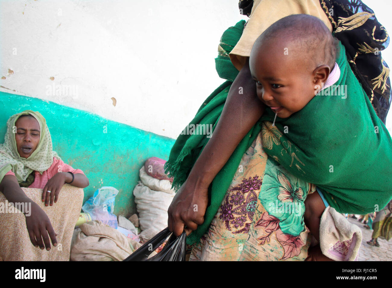 A woman carries her baby on her back in the market of Harar , Ethiopia Stock Photo