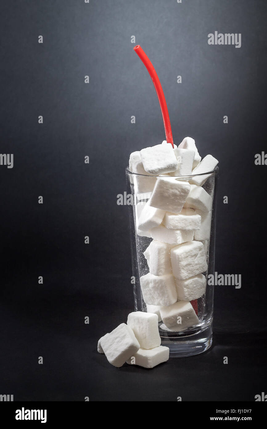 Glass full of sugar cubes with straw. Concept of unhealthy drinks. Copy space Stock Photo