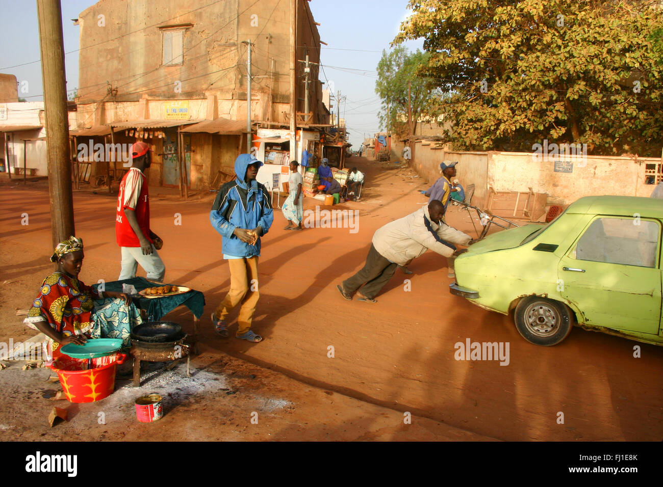 Street scene in Mopti , Mali - A man pushes a broken down car in the streets of Mopti in the early morning Stock Photo
