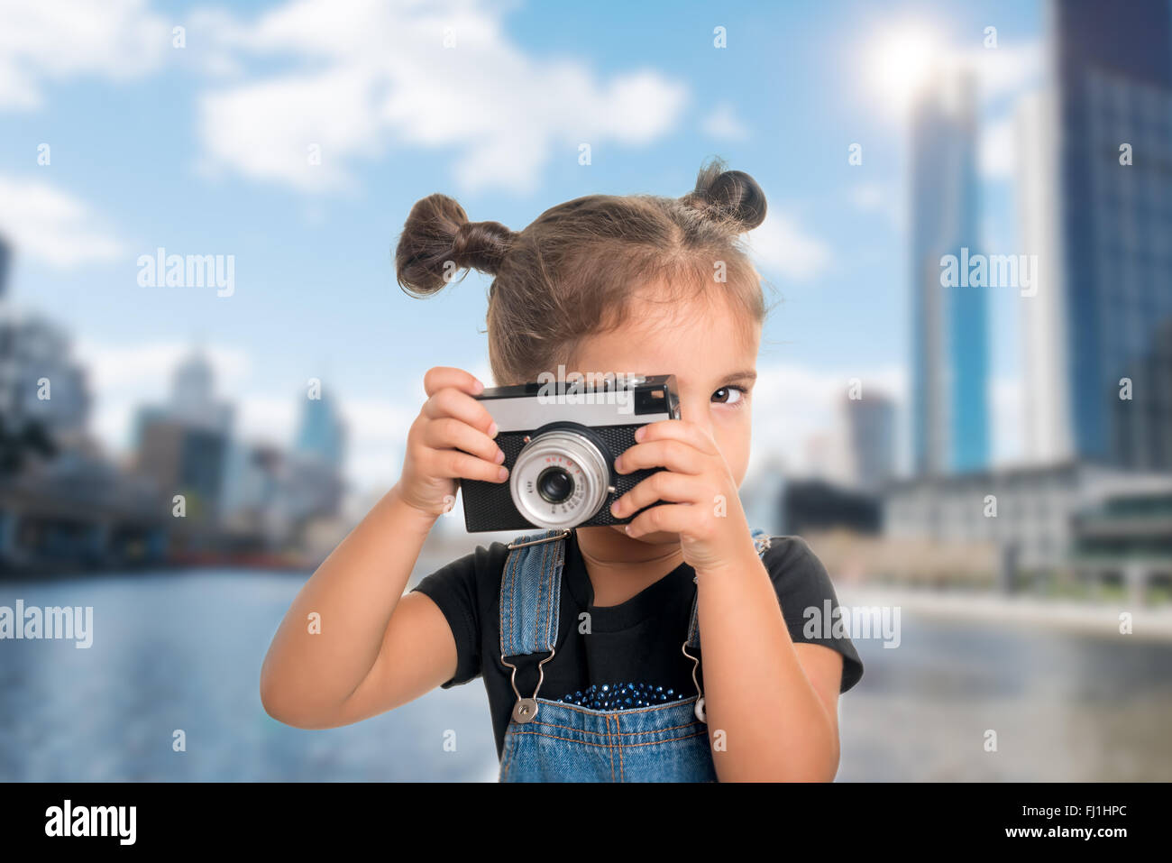 A little cute baby girl taking a picture with vintage camera over ...