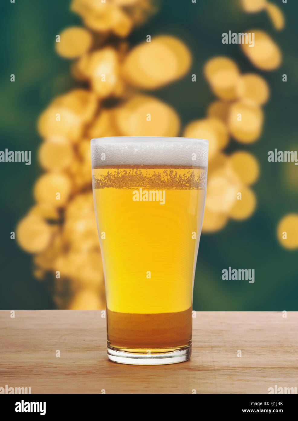 Glass of beer on wooden in light bokeh blurred background Stock Photo