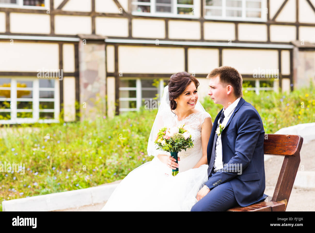 Romantic wedding couple sitting on a bench in the park Stock Photo - Alamy