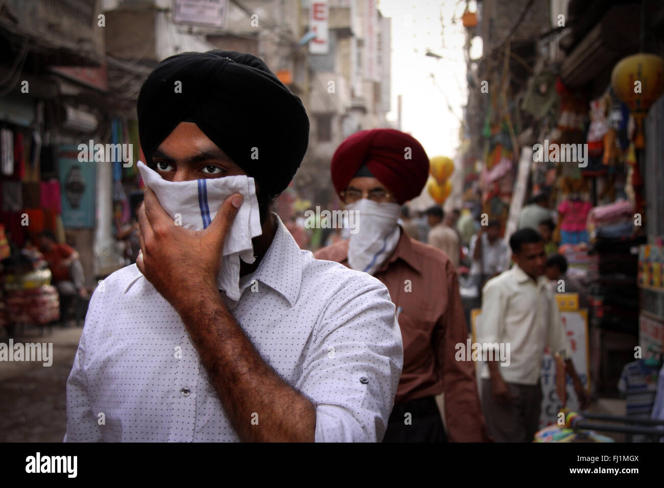 Sikh men walk in a street of New Delhi with turban and covering their faceIndia Stock Photo