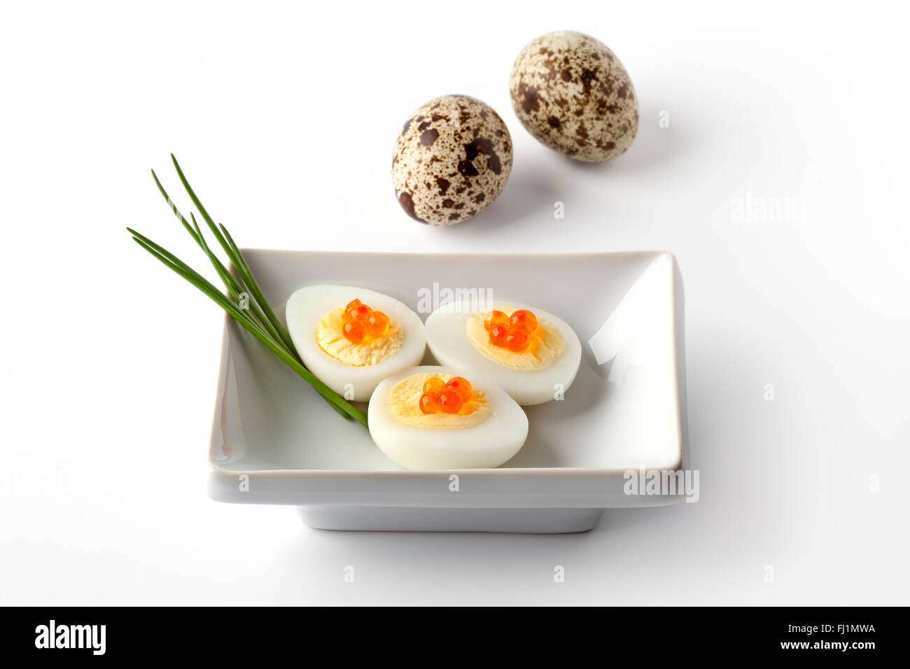 Boiled quail eggs with trout eggs and chive on white background Stock Photo