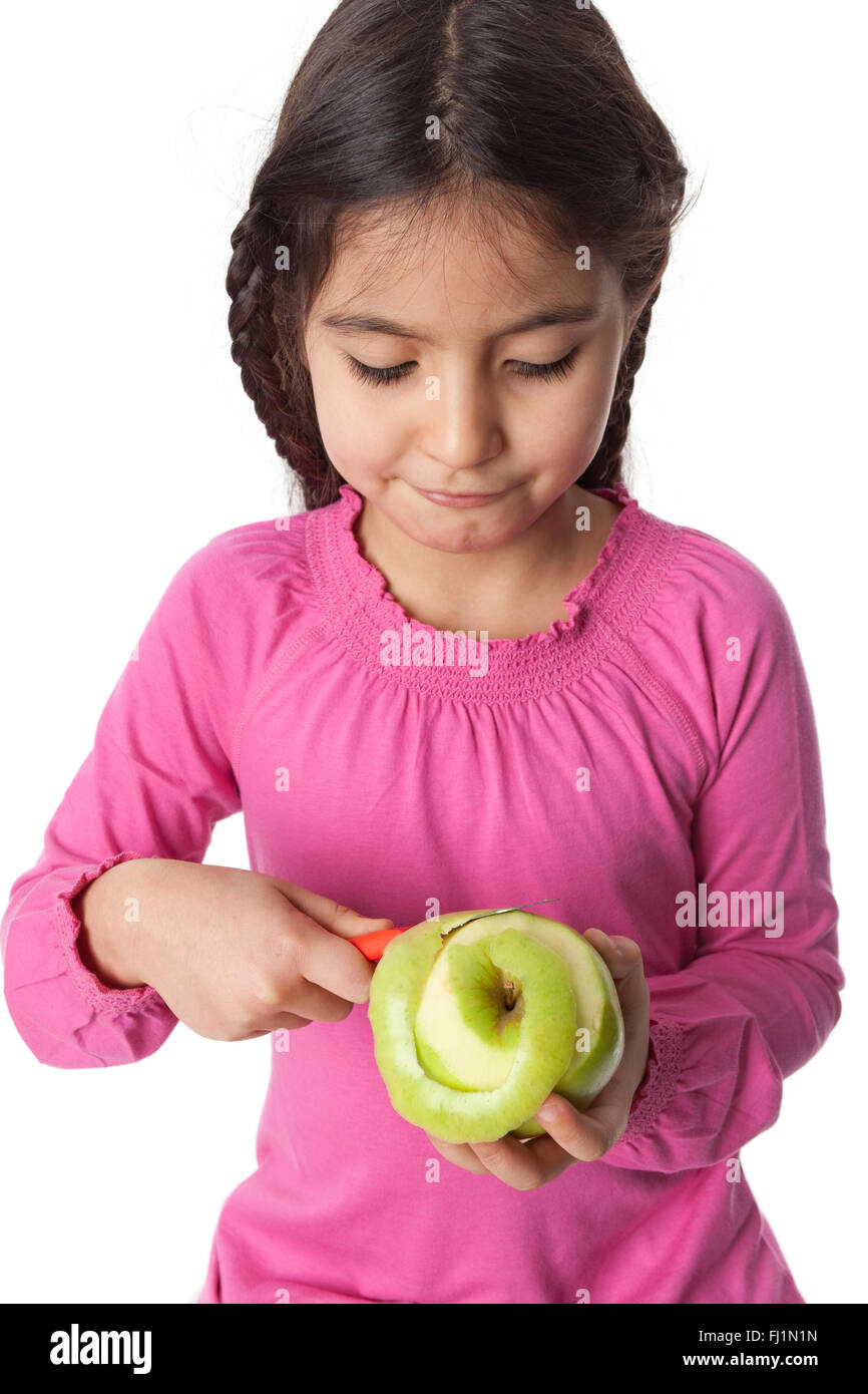 Little girl peeling an apple with a knife on white background Stock Photo