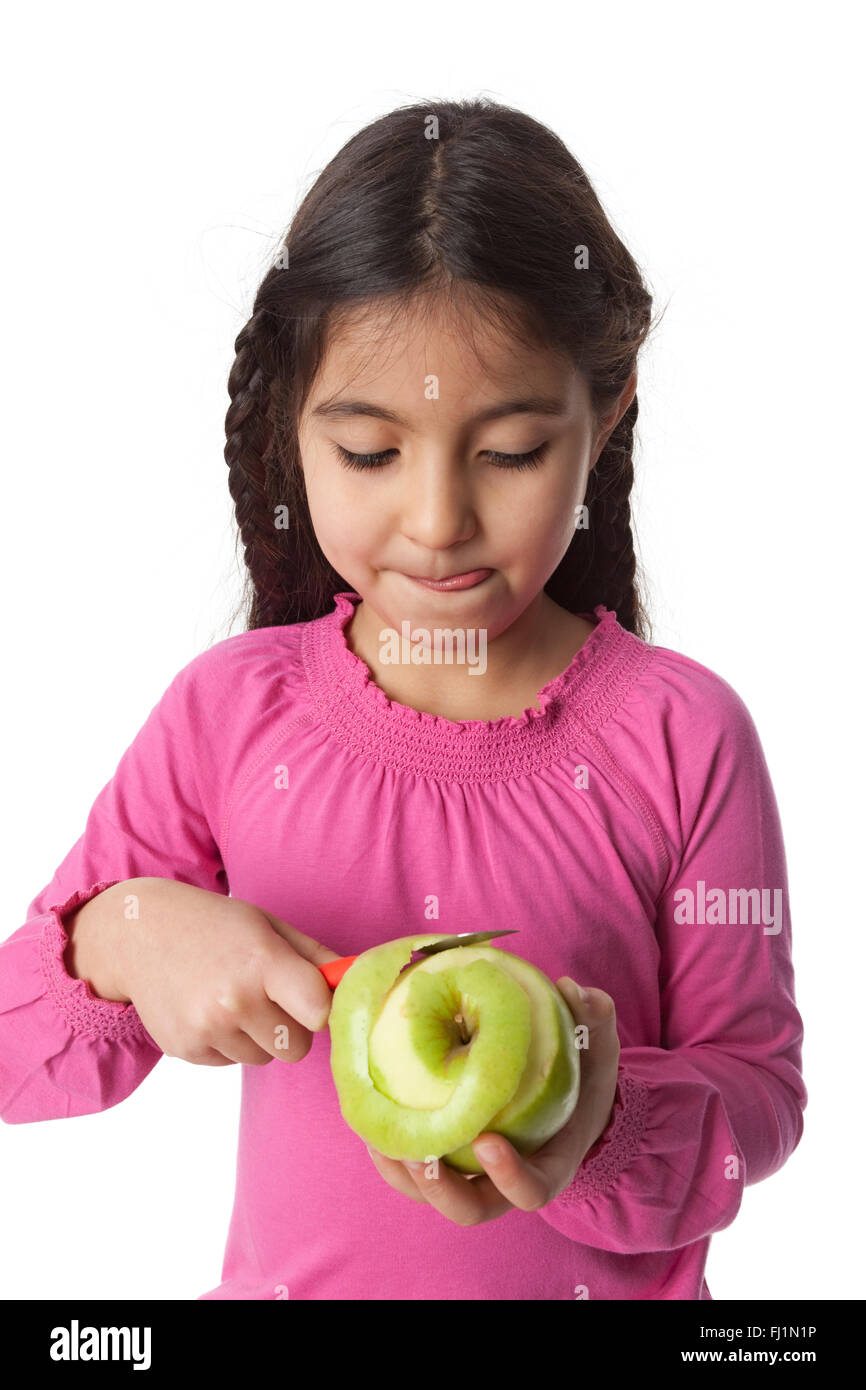 Little girl peeling an apple with a knife on white background Stock Photo