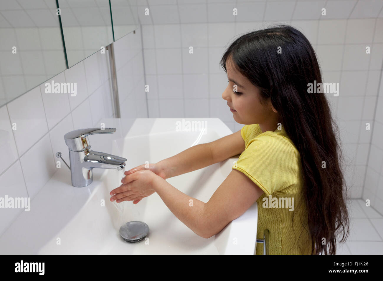 Little girl is washing her hands in the bathroom Stock Photo