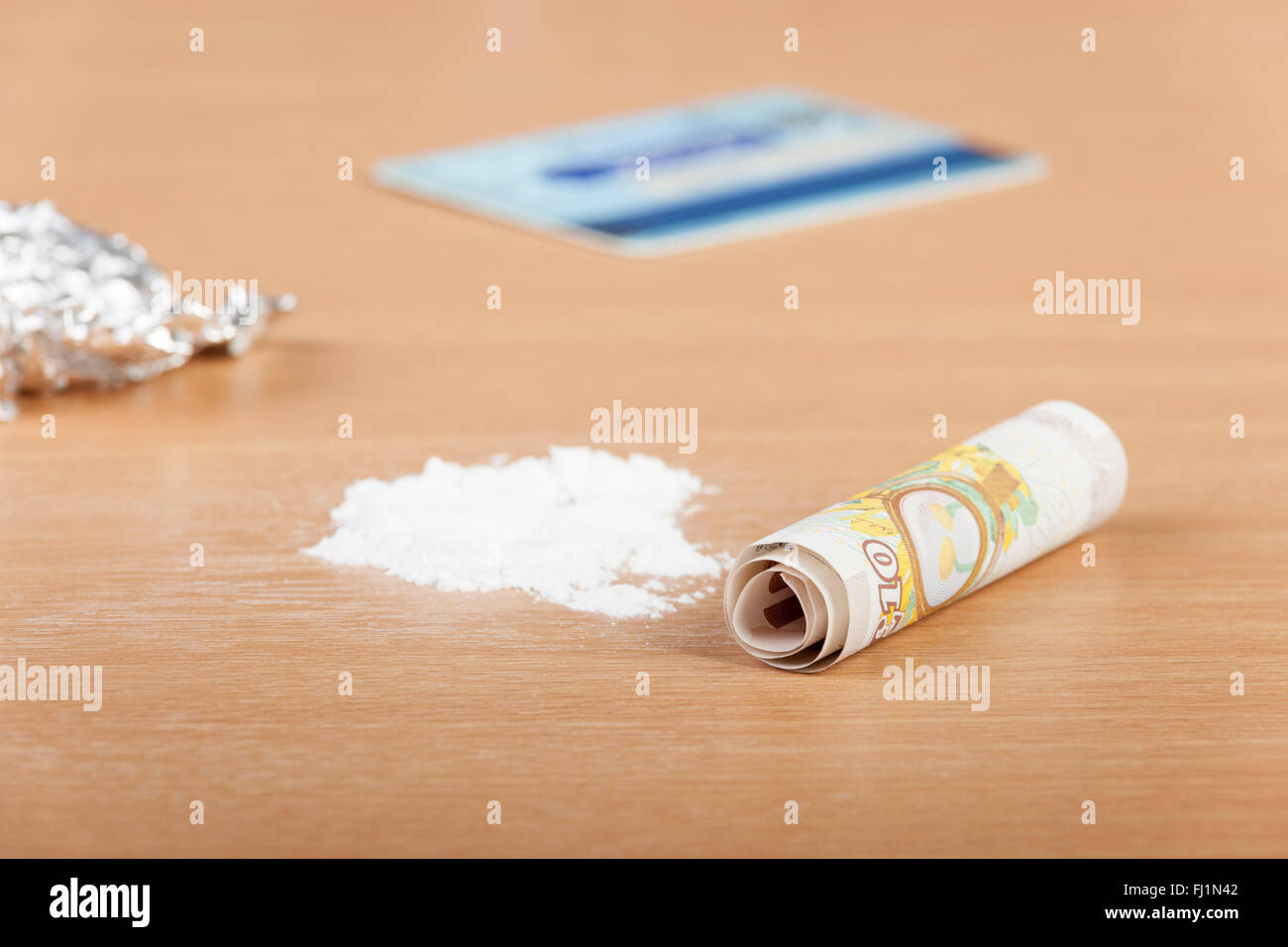 Pile of cocaine on a table ready to be lined up with a rolled up bank note and a credit card Stock Photo