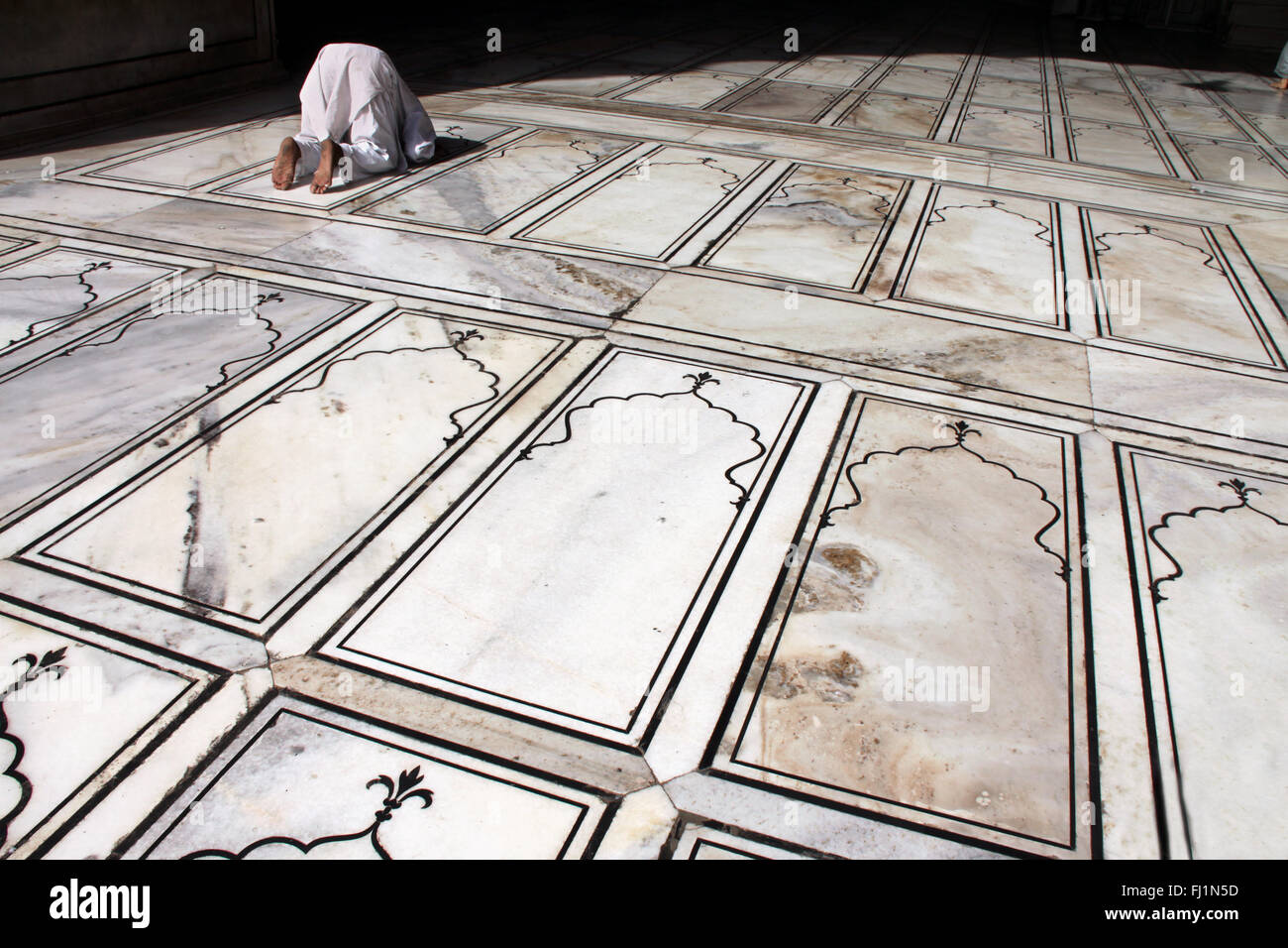 Muslim man praying on the floor in Jama masjid / great mosque of Delhi, India Stock Photo