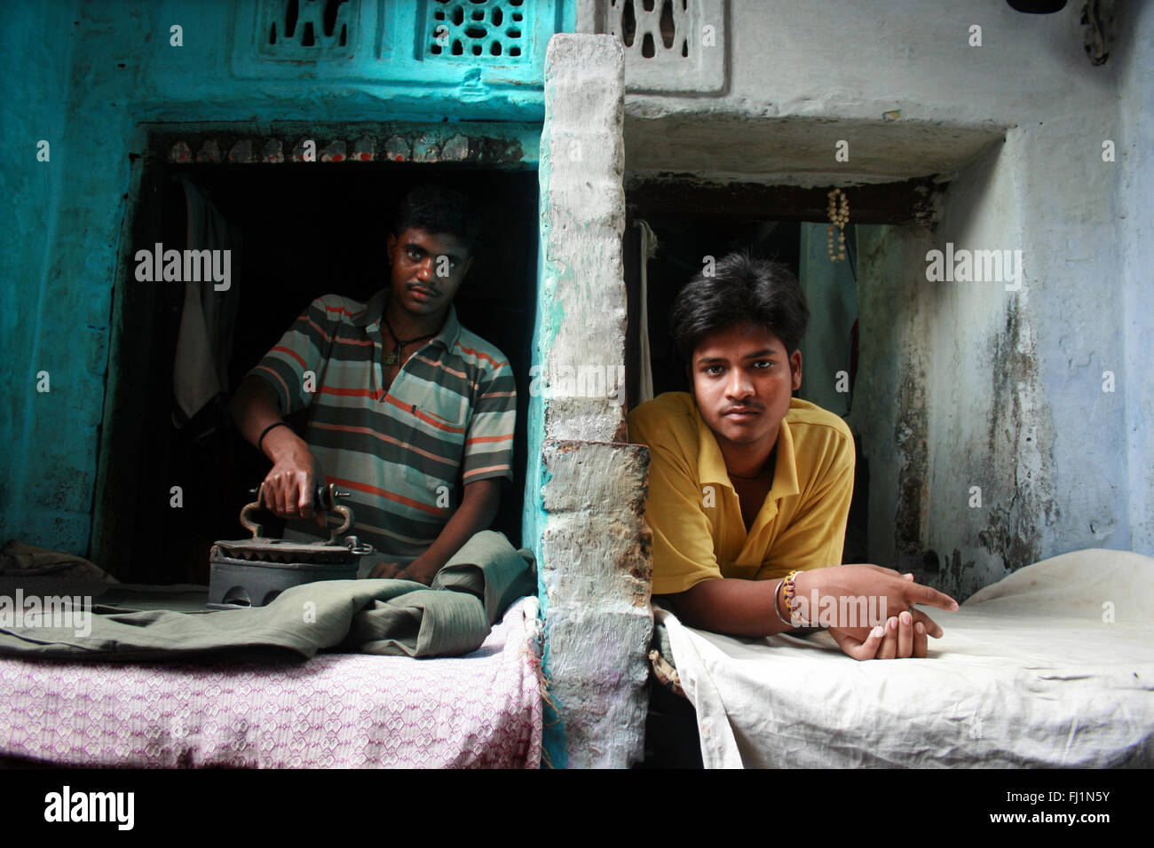 Two men workers are ironing clothes in Old city of Varanasi ,  India Stock Photo