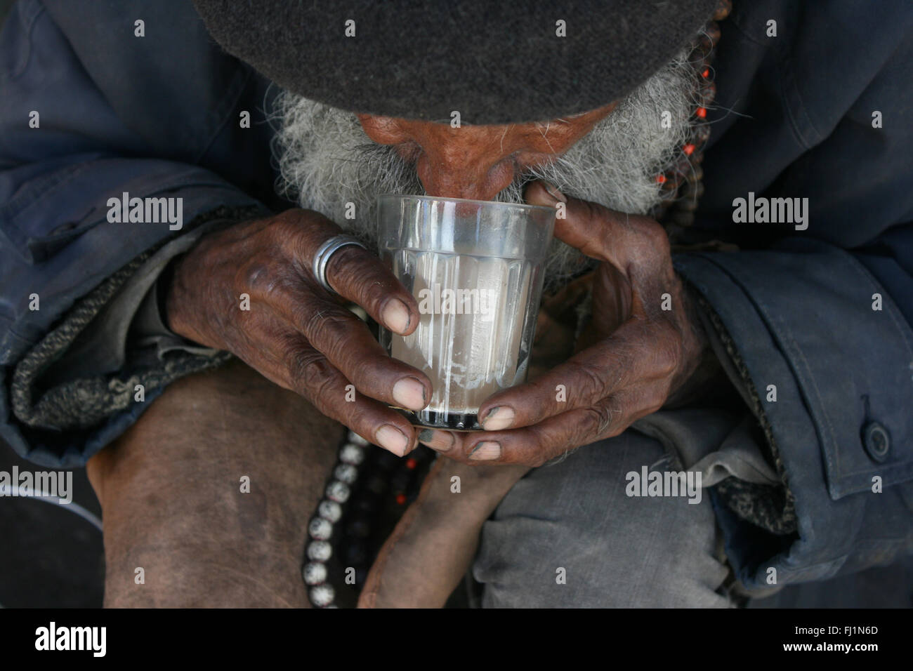 Poor old man drinking tea (chaï) in traditional glass, Shimla , India Stock Photo