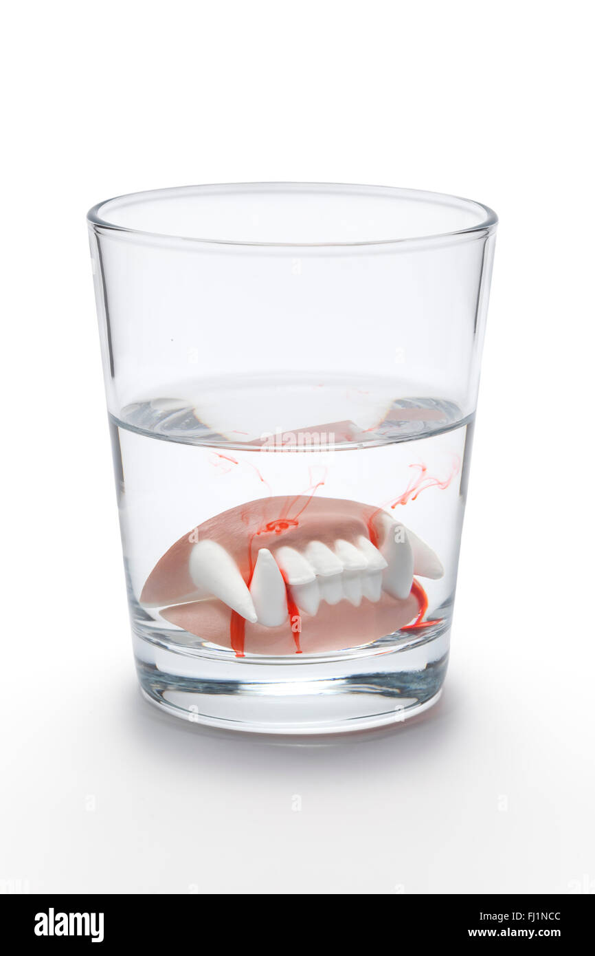 Dental prothesis with blood of a vampire in a glass of water on white background Stock Photo