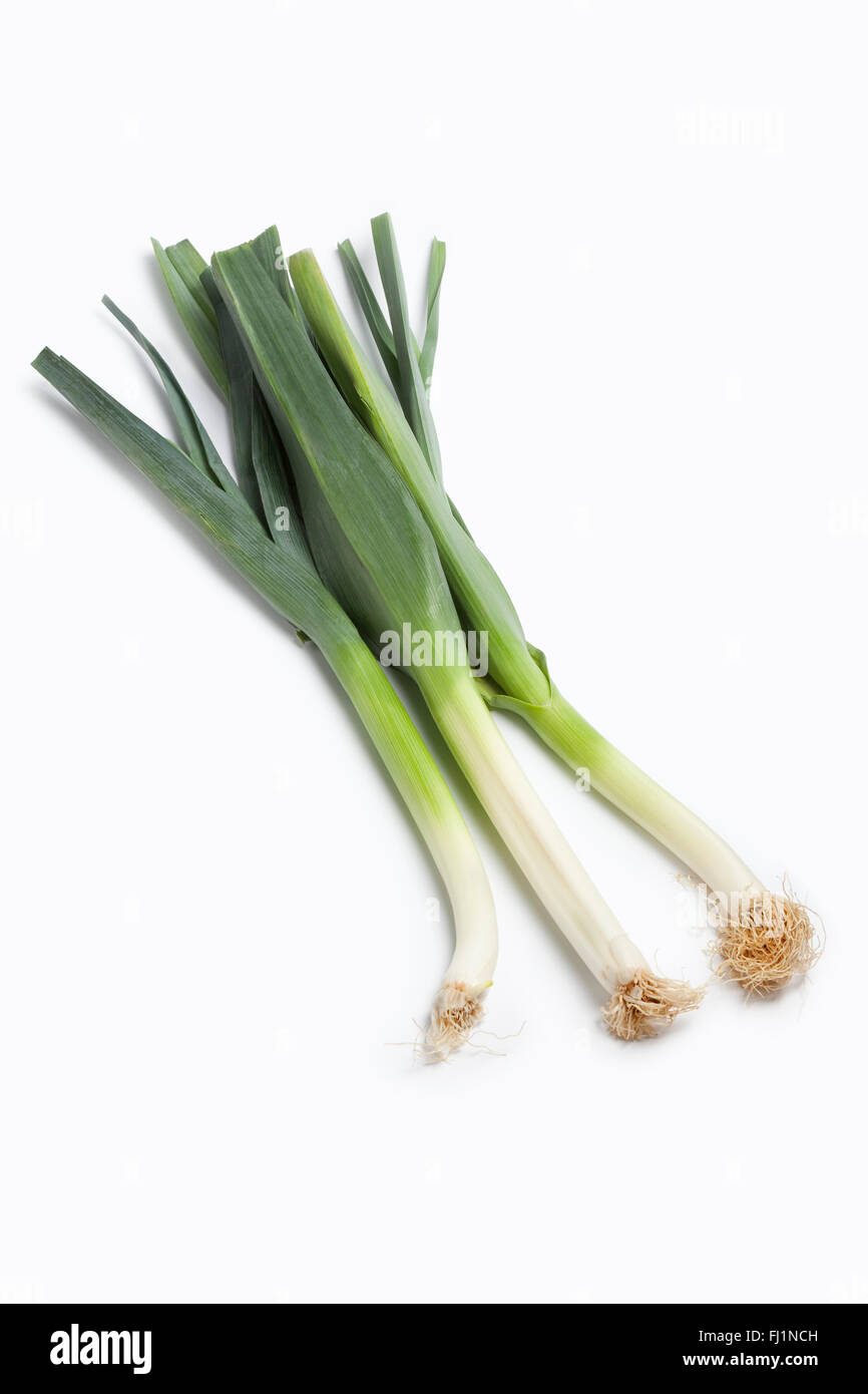 Three whole fresh raw stems of green leeks, Allium porrum, isolated white background Stock Photo