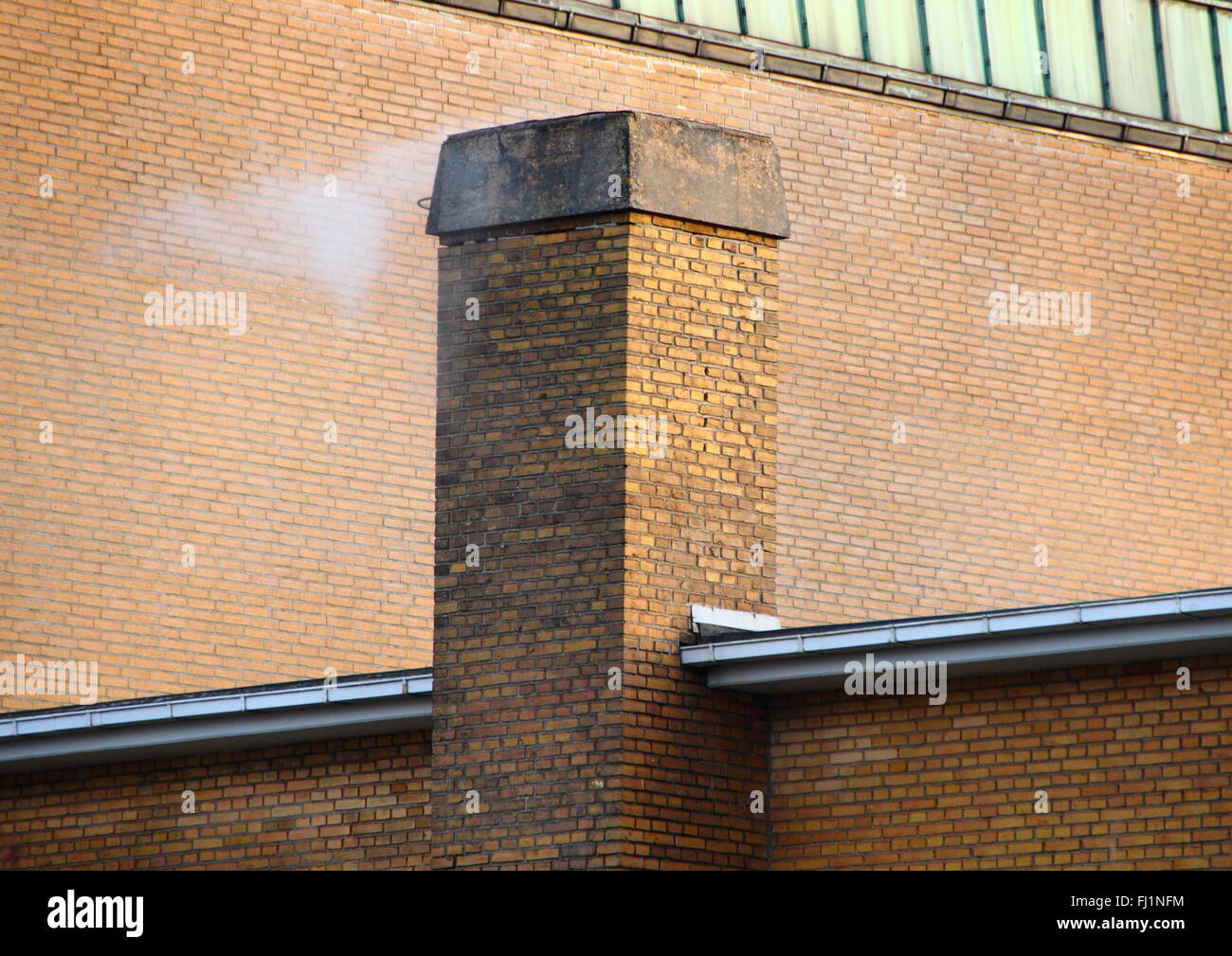 Smoking Chimney on Yellow Brick Tile Building with Shadow Stock Photo