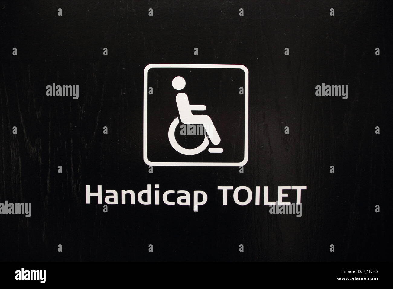 Isolated White Handicap Disabled Toilet Sign on Black Wood Stock Photo