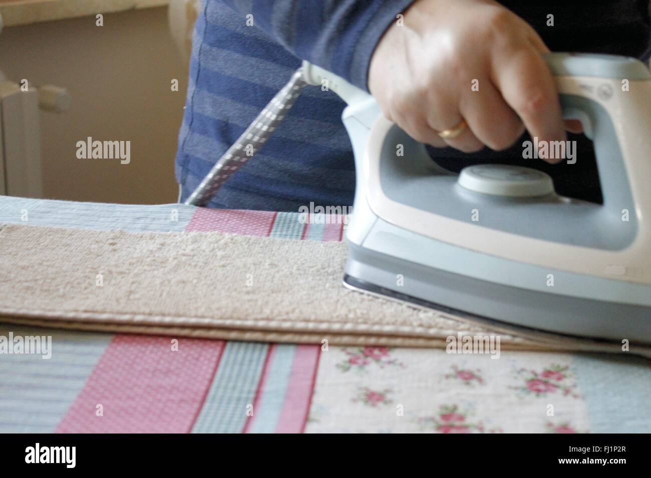 Ironing a towel with a steam iron on an ironing board Stock Photo Alamy