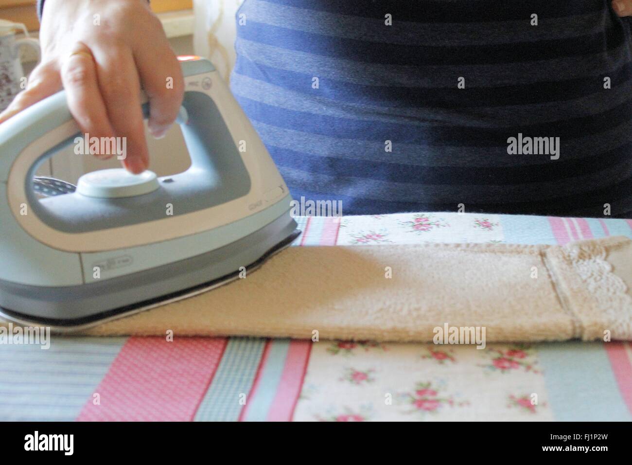 Ironing a towel with a steam iron on an ironing board Stock Photo Alamy