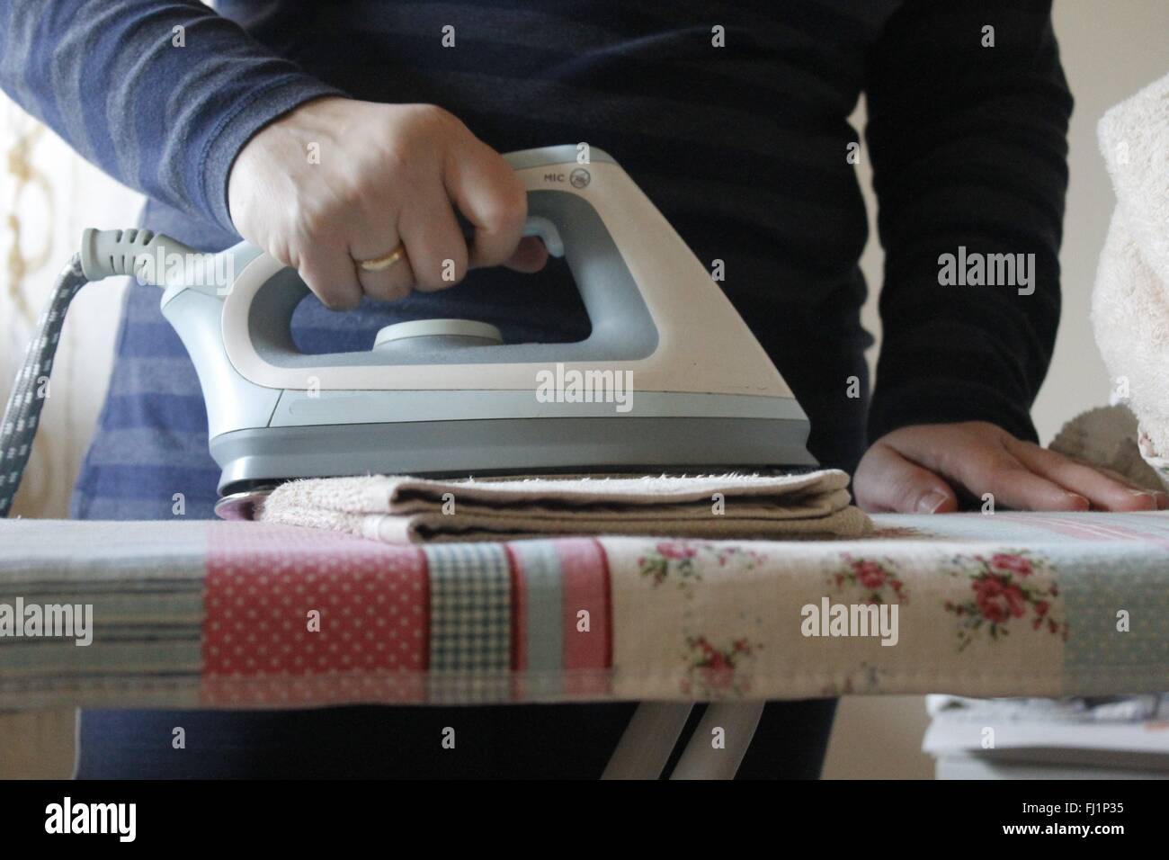 Ironing a towel with a steam iron on an ironing board Stock Photo Alamy