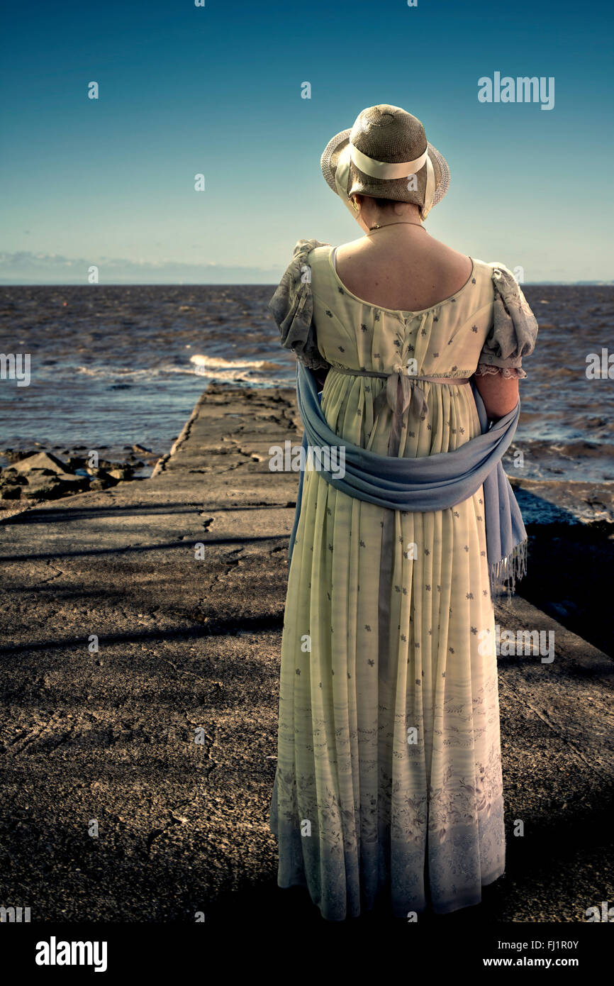 Regency dressed woman looking out to sea Stock Photo